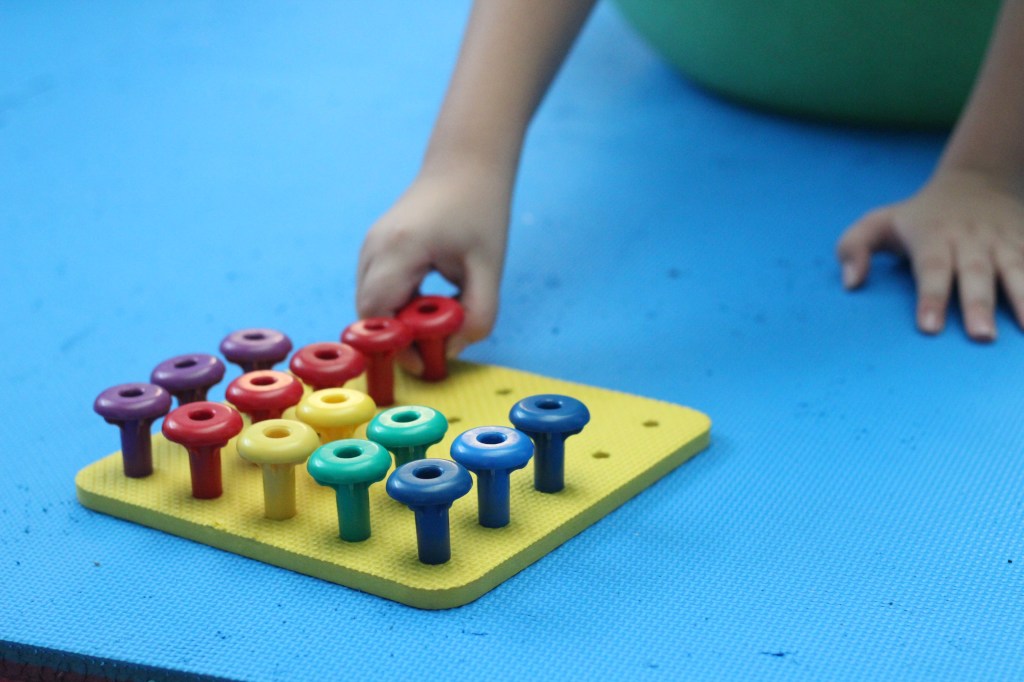Niño realizando terapia de integración sensorial en Integra Vidas Panamá, tomando trompetas de una estructura durante actividad terapéutica.