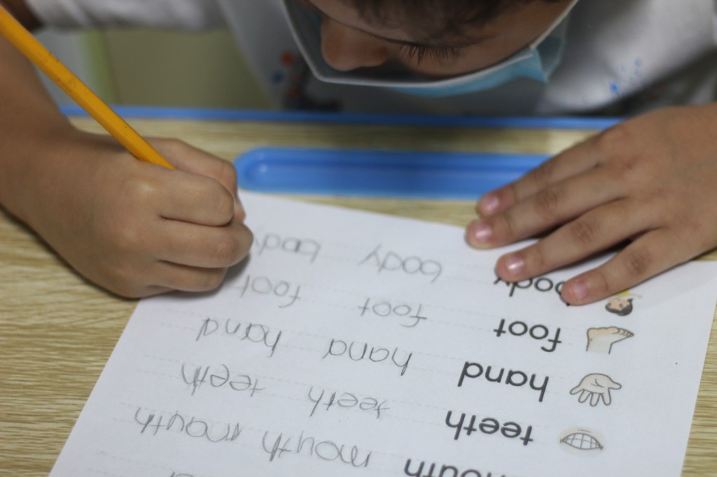 Niño en Integra Panamá escribiendo palabras en inglés como parte de una clase adaptada.