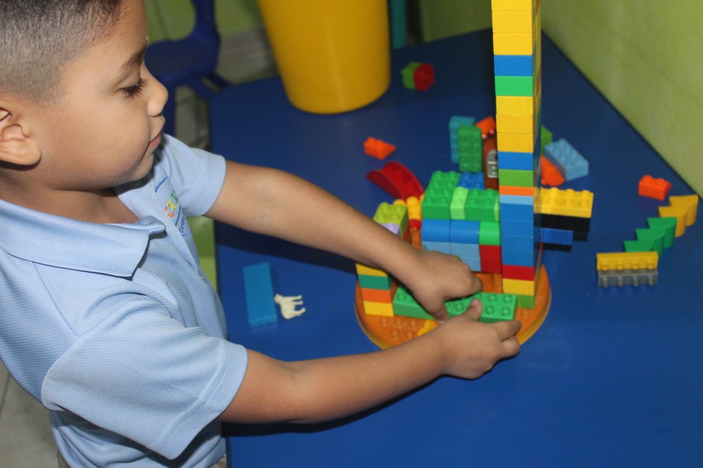 Niño construyendo con bloques de colores durante sus clases en Integra Vidas, desarrollando habilidades cognitivas y motoras.